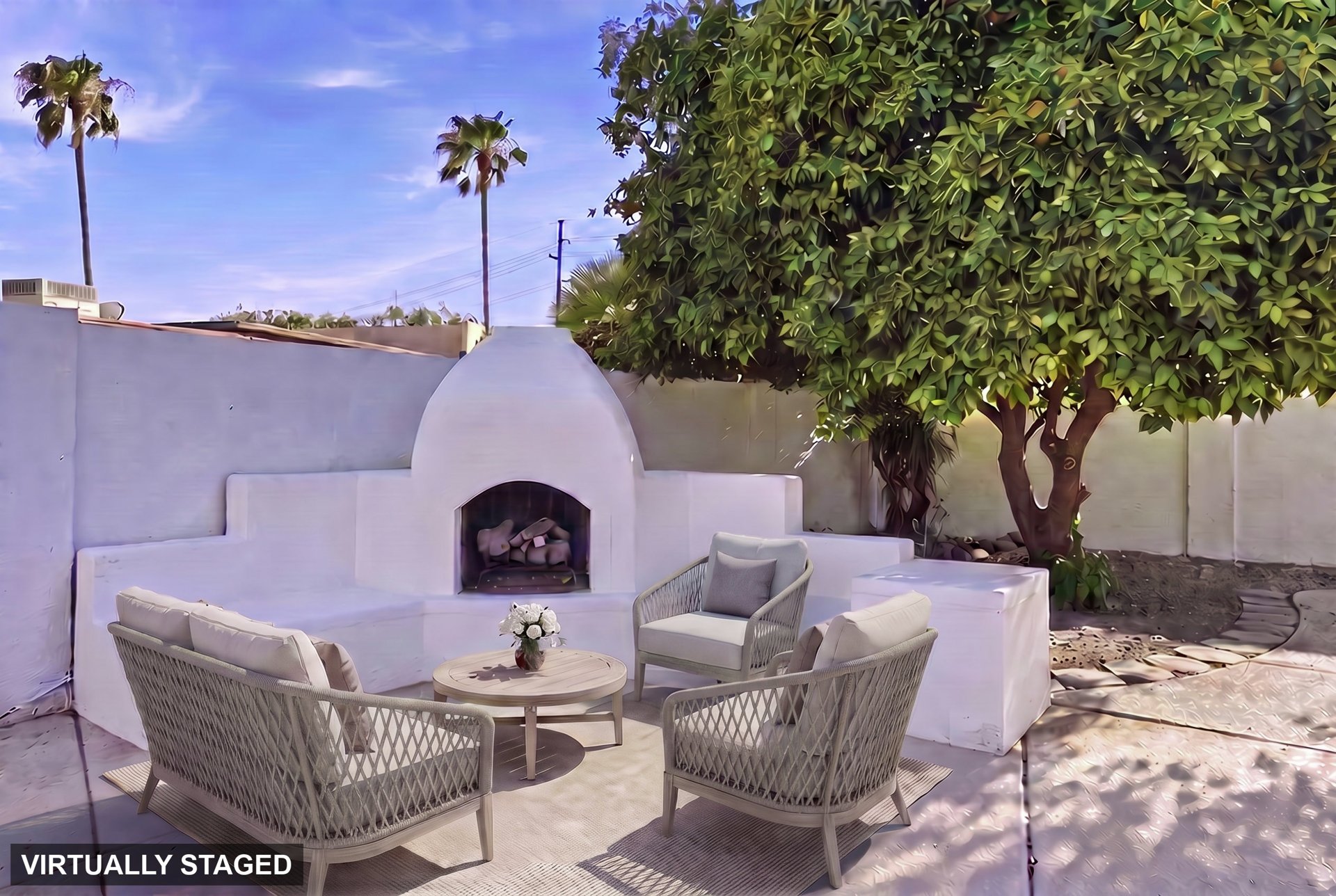 Outdoor stucco fireplace with built in seating under a mature tree