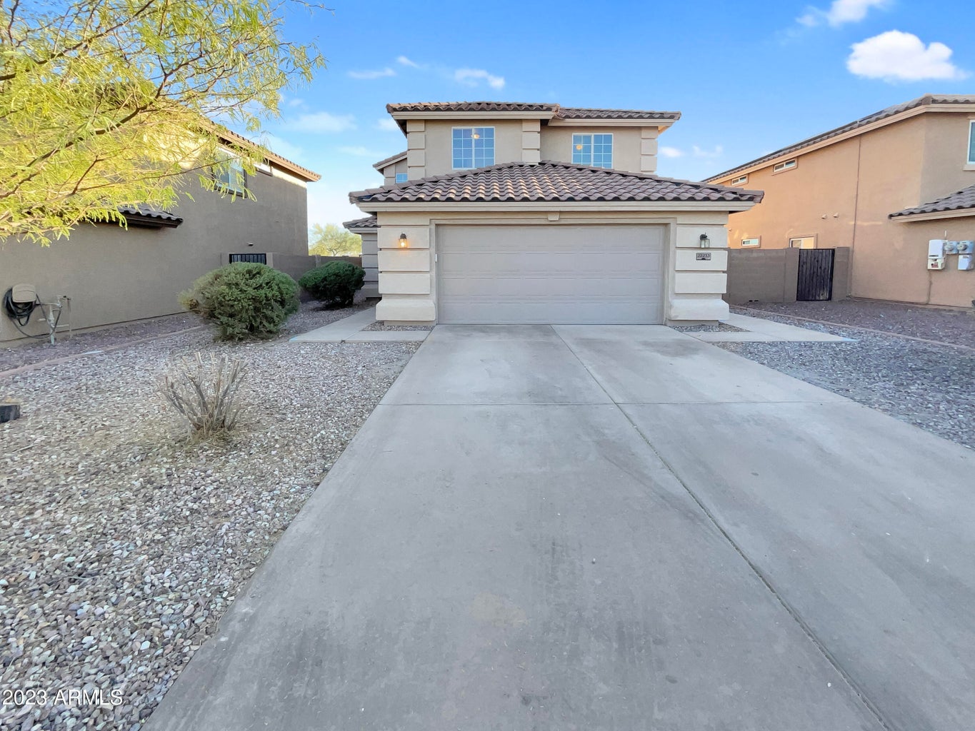 Two story home with tile roof, a front garage and desert landscaping