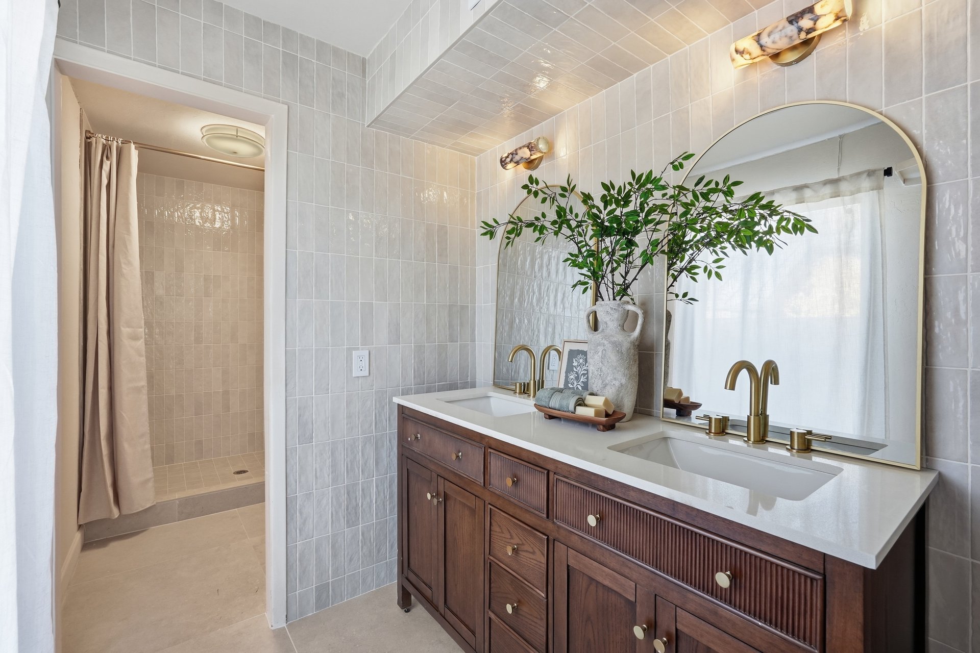 Bathroom with double vanity, arched mirror and tiled walls